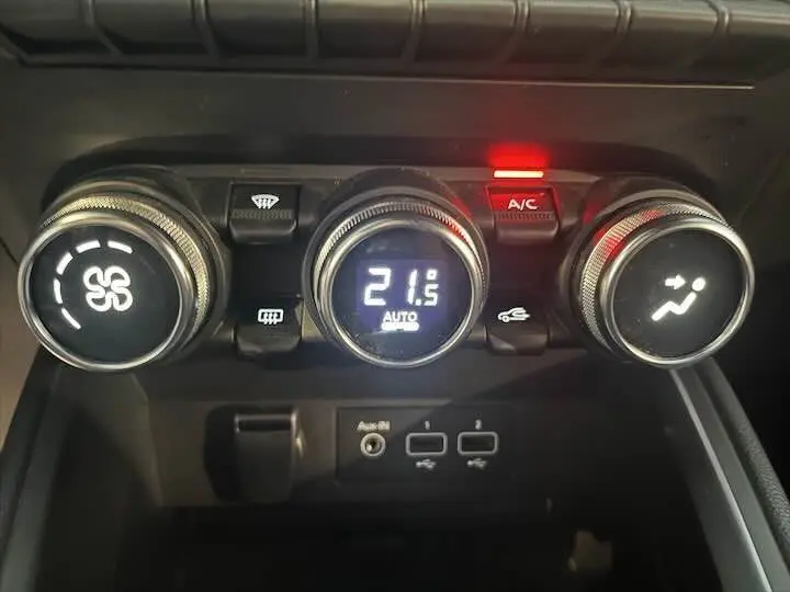 Gros plan sur les commandes de climatisation de la Renault Clio V avec affichage digital à 21,5°C et bouton A/C allumé.