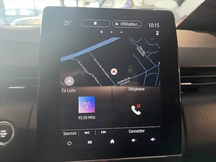 Écran tactile central de la Renault Clio V affichant la navigation et la radio, intérieur noir moderne.