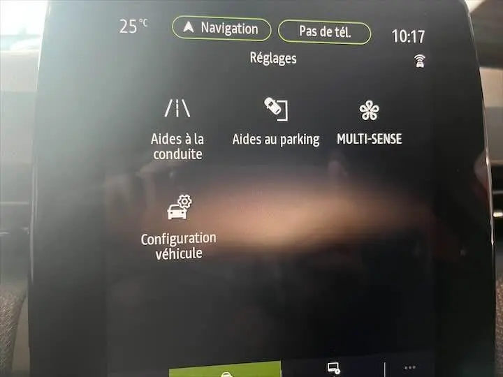 Écran tactile central de la Renault Clio V rouge flamme, affichant les réglages d'aides à la conduite et parking.