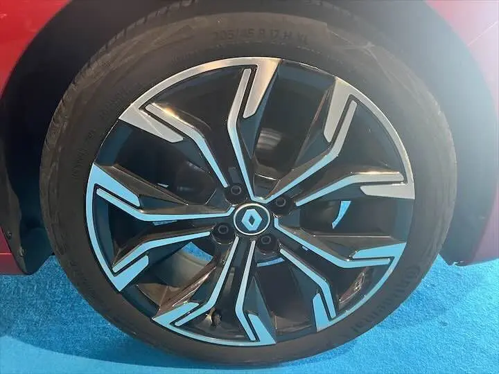 Gros plan sur la jante noire et argentée d'une Renault Clio V rouge flamme métal, vue côté gauche.