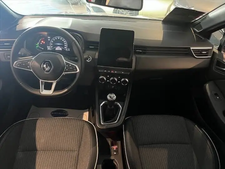 Vue intérieure avant de la Renault Clio V 1.0 TCE 90 Intens, tableau de bord moderne avec écran tactile vertical et volant multifonction.