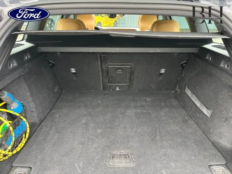Coffre ouvert d'une Volvo V60 T8 gris Savile, montrant un intérieur spacieux avec banquette arrière cuir brun visible.