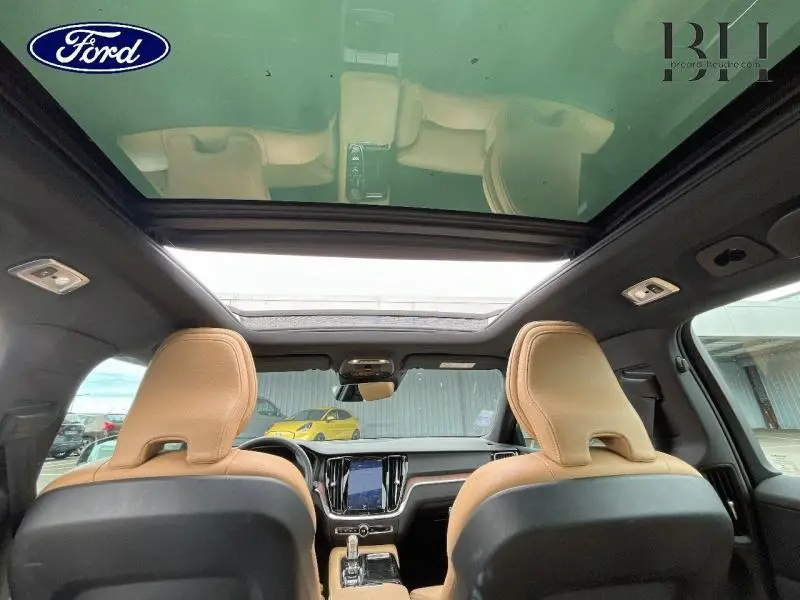 Vue intérieure arrière de la Volvo V60 T8 gris Savile, sièges cuir brun et toit panoramique en verre ouvert