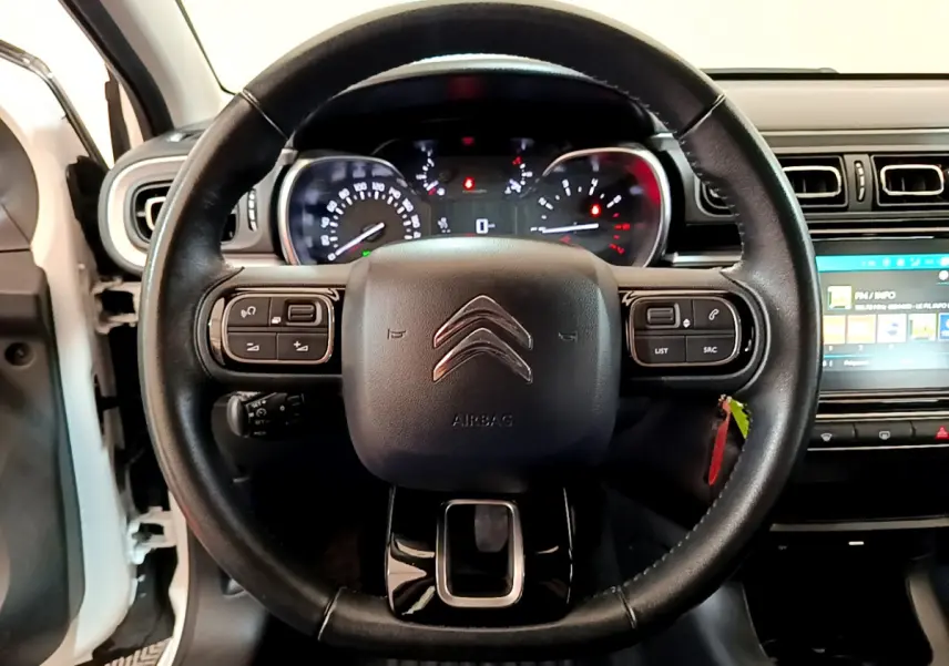 Vue rapprochée du volant cuir noir de la Citroën C3 blanche 2019 avec tableau de bord et écran tactile visible.