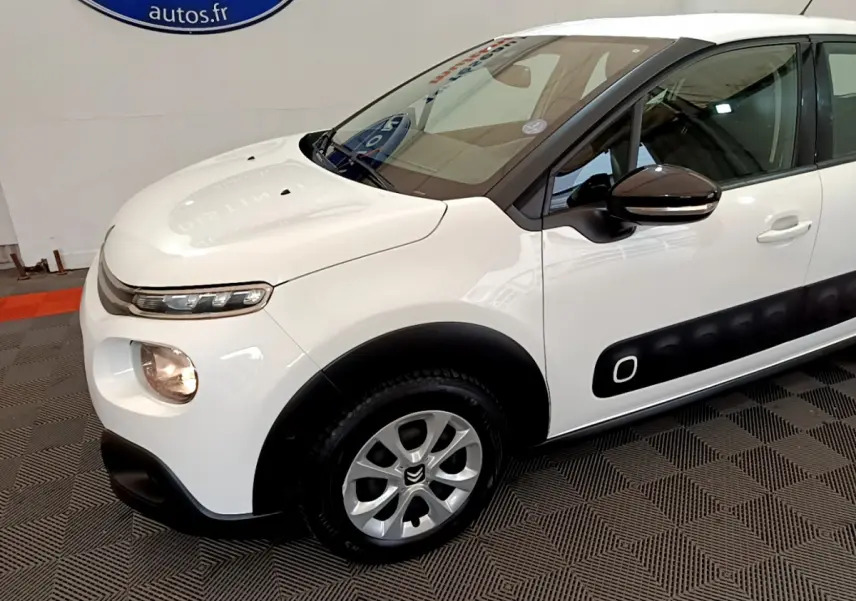 Vue 3/4 avant gauche d'une Citroën C3 blanche avec protections latérales noires et jantes alliage argentées.