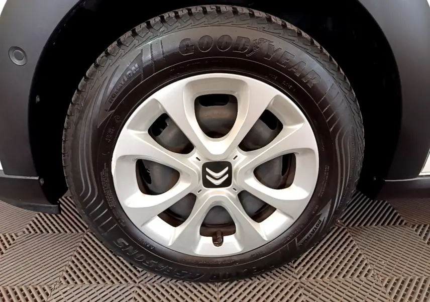 Gros plan sur la roue avant gauche d'une Citroën C3 blanche, jante alliage et pneu Goodyear visibles.