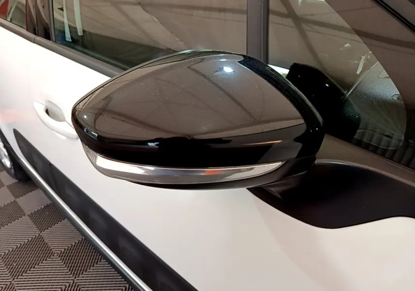 Rétroviseur noir avec clignotant intégré côté gauche sur Citroën C3 blanche vue de près en intérieur.