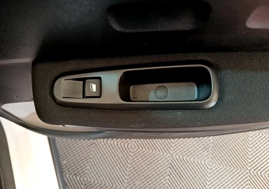 Gros plan sur la poignée intérieure noire et le bouton de lève-vitre côté gauche d'une Citroën C3 blanche de 2019.
