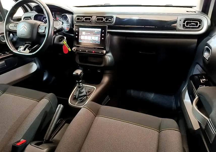 Intérieur avant de la Citroën C3 blanche 2019, tableau de bord noir avec écran tactile et volant cuir multifonctions.