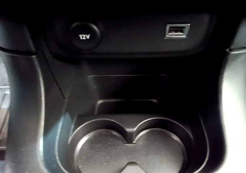 Gros plan sur le porte-gobelets noir et prises 12V et USB dans l'habitacle de la Citroën C3 blanche de 2019.