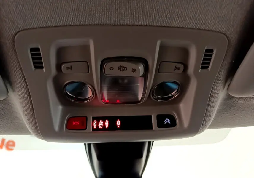Vue en gros plan du plafonnier intérieur de la Citroën C3 blanche avec boutons SOS et éclairage intégré.