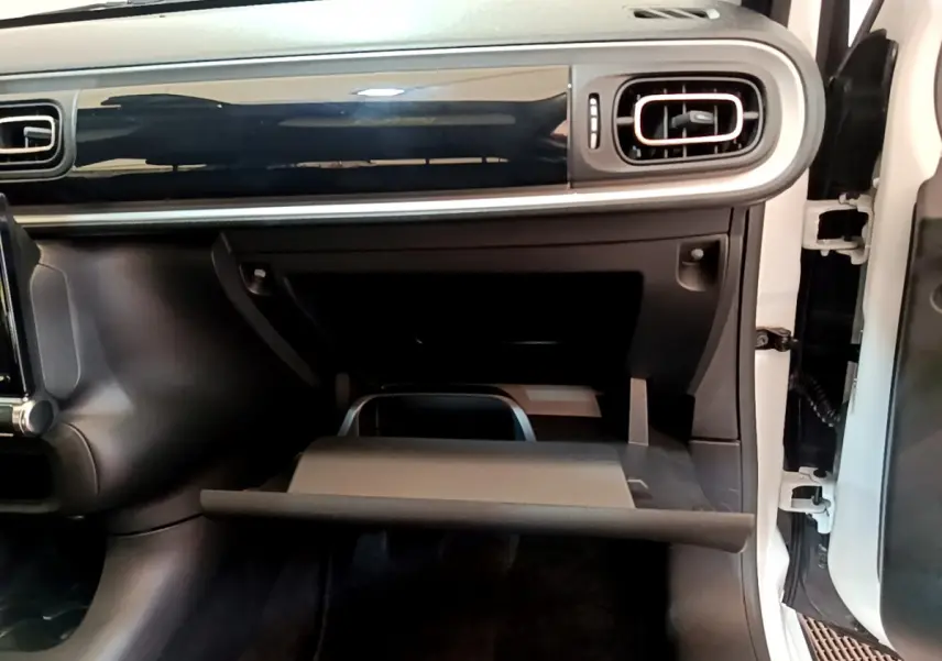 Vue intérieure côté passager de la Citroën C3 blanche 2019, tableau de bord noir avec boîte à gants ouverte.