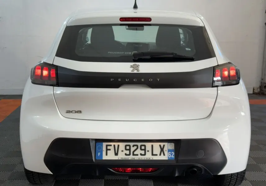 Vue arrière d'une Peugeot 208 blanche avec feux arrière allumés et plaque d'immatriculation française visible.