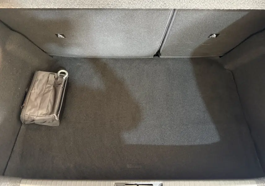 Vue plongeante sur le coffre gris foncé de la Peugeot 208 PureTech 75 avec une trousse de secours posée à gauche.
