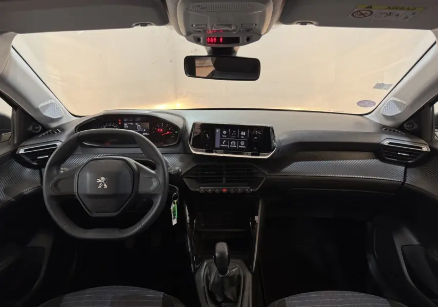 Vue frontale de l'habitacle noir de la Peugeot 208 PureTech 75 S&S Like avec tableau de bord et écran tactile central.