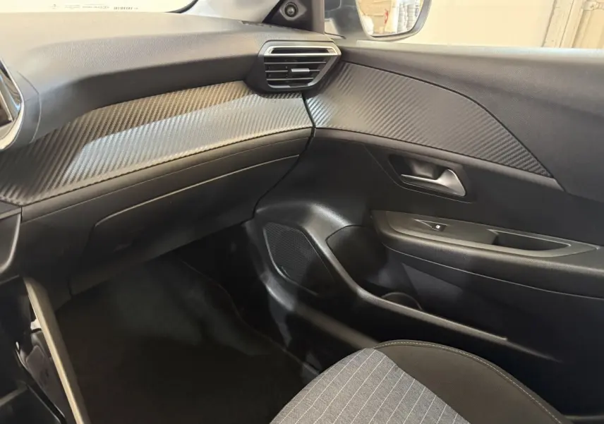 Intérieur côté passager de la Peugeot 208 PureTech 75 S&S Like 2020, avec tableau de bord noir et inserts effet carbone.