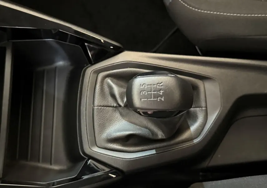 Vue rapprochée du levier de vitesses manuel noir de la Peugeot 208 PureTech 75 S&S Like 2020, intérieur sombre.