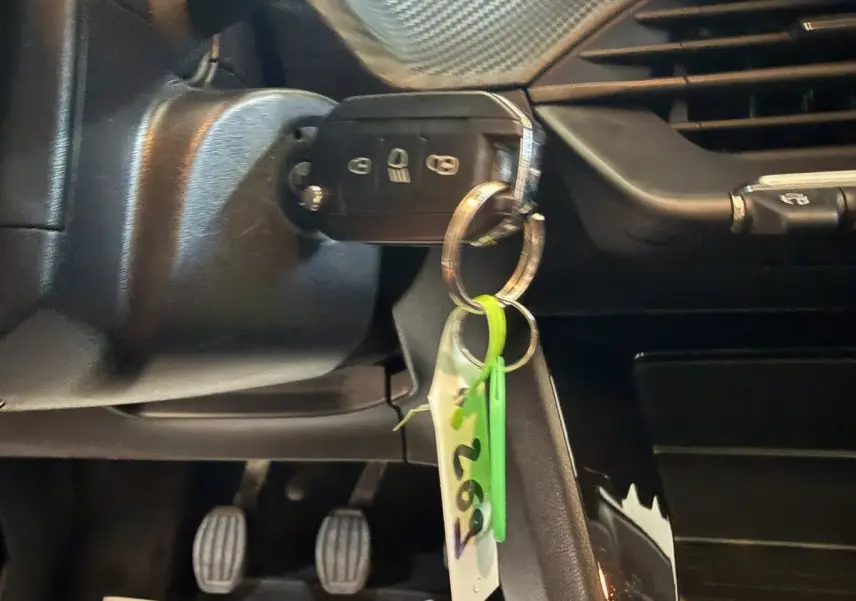 Gros plan sur la clé de contact insérée dans le contacteur d'une Peugeot 208 PureTech 75 S&S Like, intérieur noir.