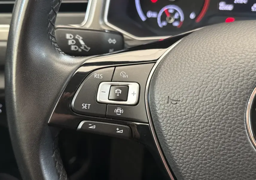 Gros plan sur les commandes du volant cuir noir du Volkswagen T-Roc 2.0 TDI, affichage digital en arrière-plan.