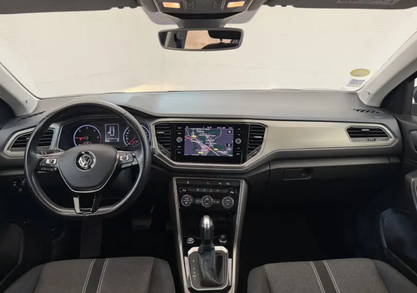 Vue frontale de l'habitacle du Volkswagen T-Roc bleu, avec tableau de bord numérique et écran tactile central.