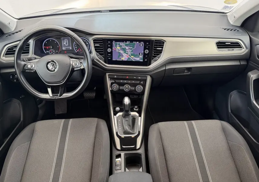 Vue intérieure avant du Volkswagen T-Roc 2.0 TDI bleu, montrant tableau de bord, volant cuir et écran tactile central.