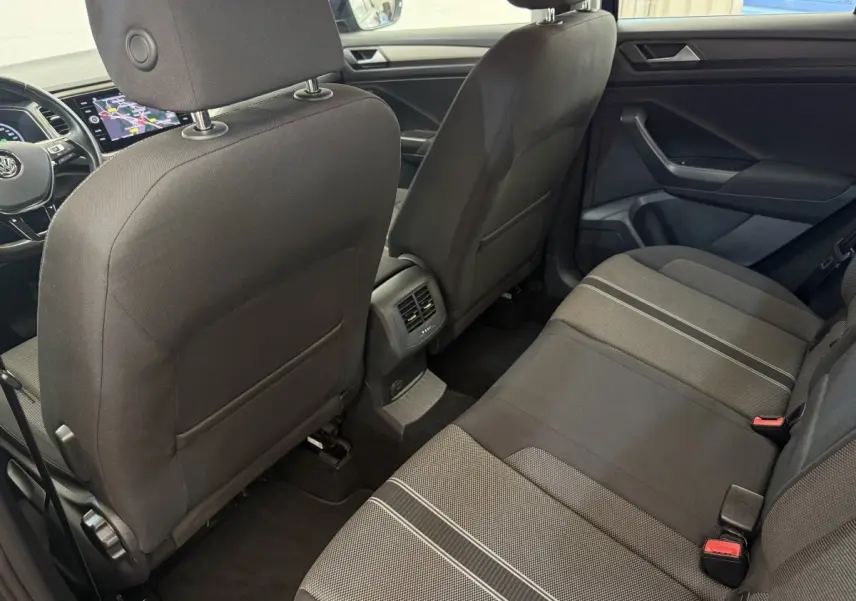 Vue intérieure arrière du Volkswagen T-Roc 2020, sièges tissu noirs avec détails gris et console centrale avec aérateurs.