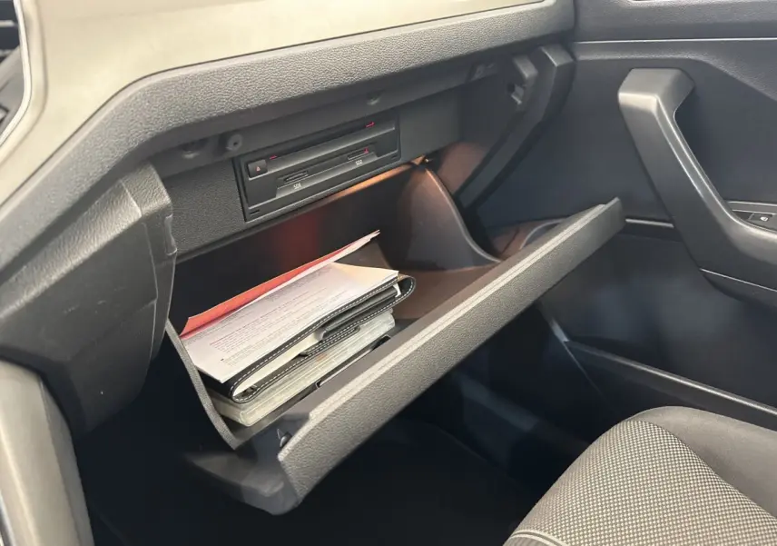 Vue intérieure du coffre à gants ouvert côté passager d'un Volkswagen T-Roc 2.0 TDI bleu, montrant des documents rangés.