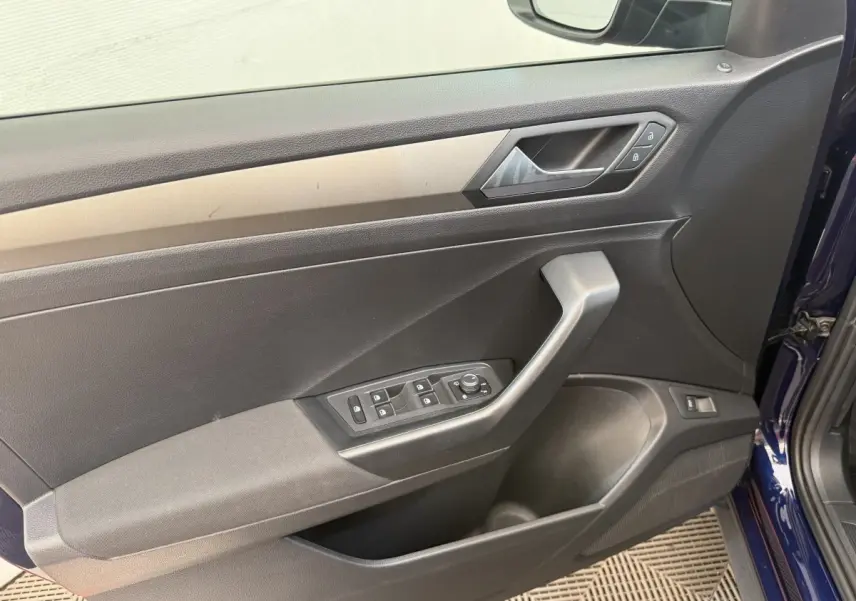 Vue intérieure côté gauche de la porte avant d’un Volkswagen T-Roc bleu avec commandes de vitres et rétroviseurs.