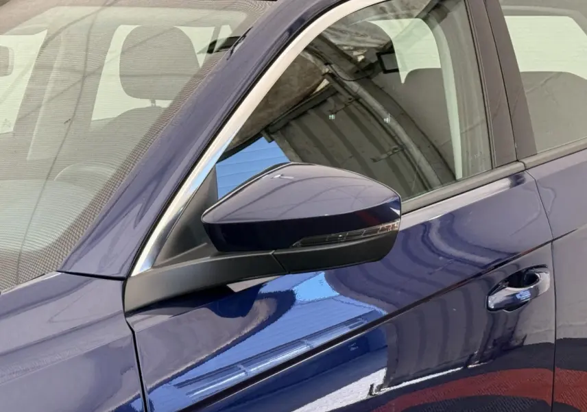 Gros plan sur le rétroviseur et la porte côté conducteur d’un Volkswagen T-Roc bleu métallisé 2020.