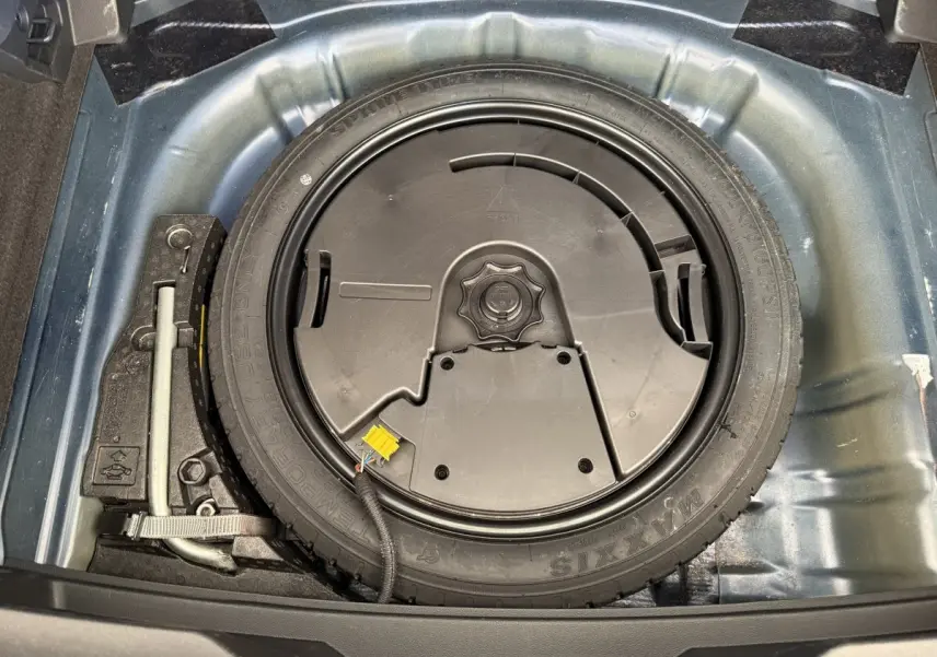 Vue plongeante sur la roue de secours et le cric dans le coffre d'un Volkswagen T-Roc bleu 2020.