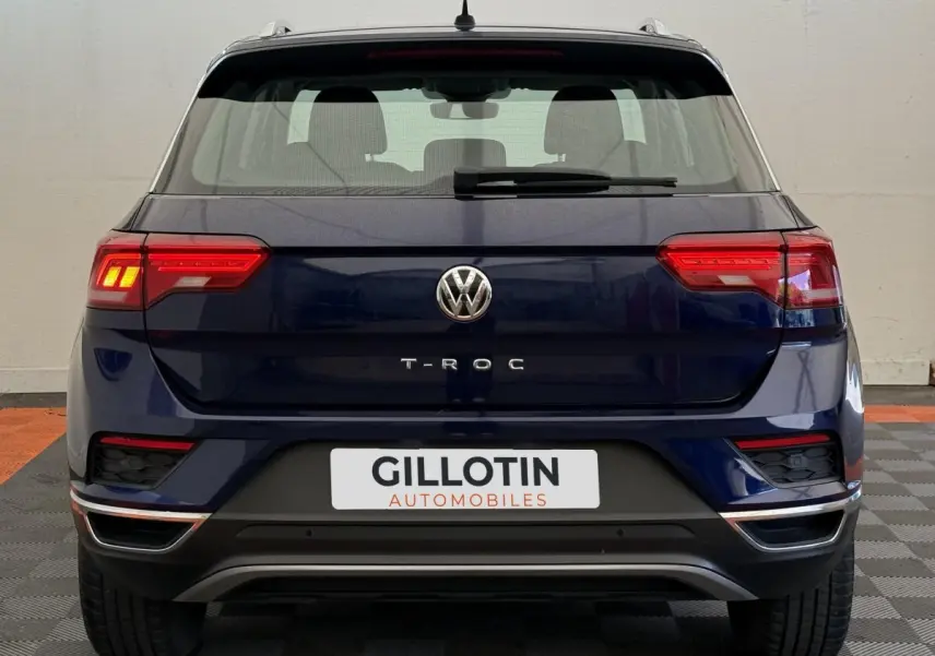 Vue arrière d'un Volkswagen T-Roc bleu 2020 avec feux LED allumés et logo VW bien visible.