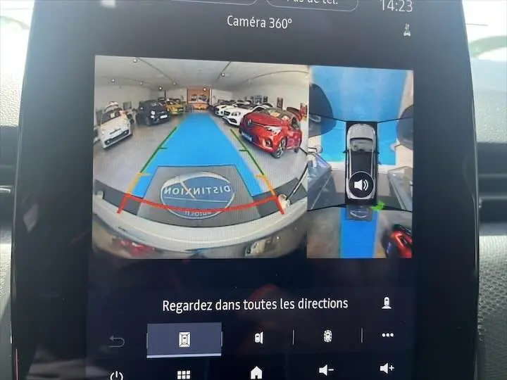 Vue écran caméra 360° montrant l'arrière d'une Renault Clio V blanc nacré en intérieur showroom.