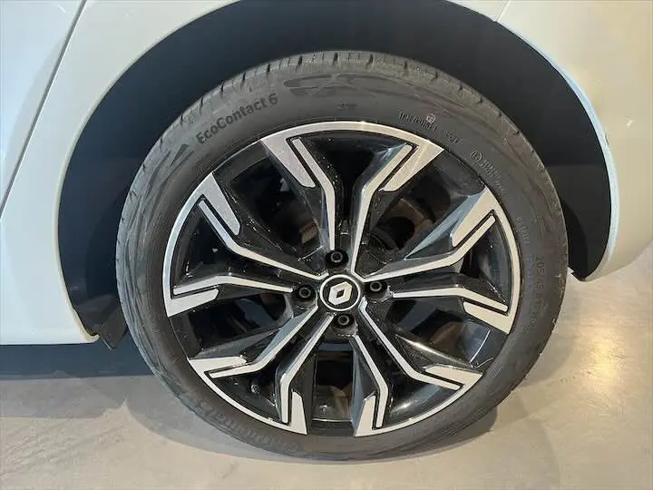 Gros plan sur la roue avant droite d'une Renault Clio V blanc nacré avec jante alliage noir et argent.