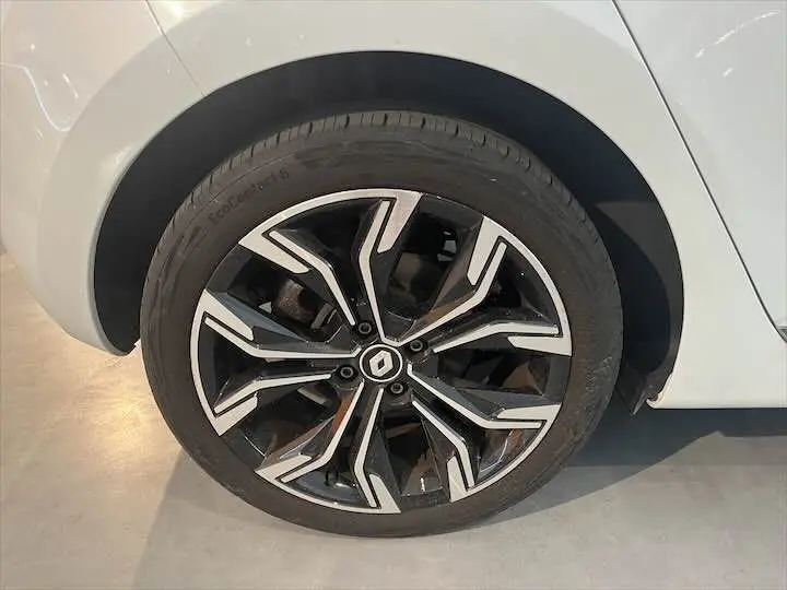 Gros plan sur la roue avant droite d'une Renault Clio V blanc nacré avec jante alliage noire et argentée au design moderne.