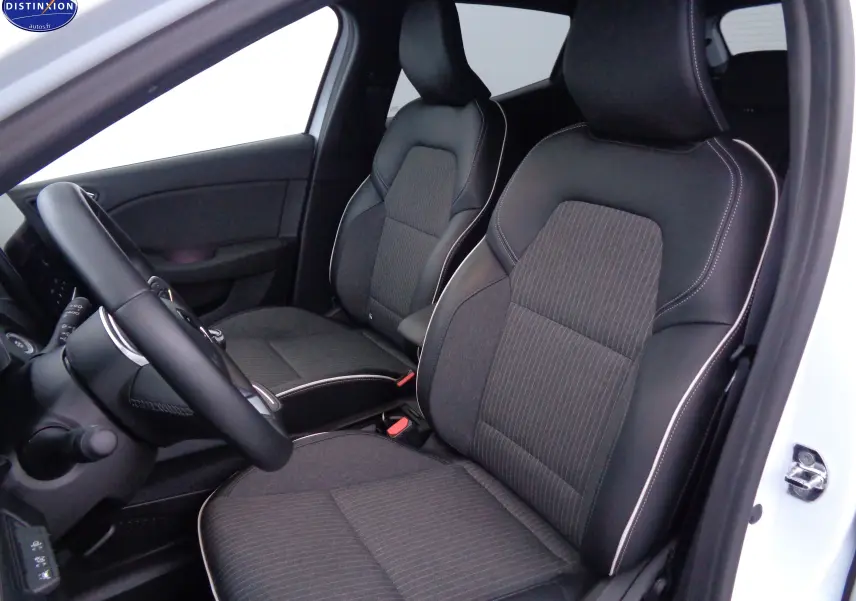 Vue intérieure côté conducteur de la Renault Clio V blanche nacrée, sièges en tissu gris et cuir noir avec surpiqûres blanches.