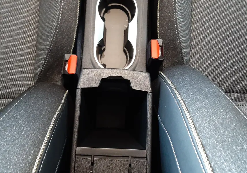 Vue plongeante sur la console centrale du Renault Captur E-Tech Hybrid 2024 avec accoudoirs en tissu gris et coutures blanches.