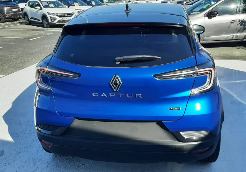 Vue arrière d'un Renault Captur E-Tech Hybrid 145ch bleu iron avec toit noir, feux LED et logo distinctif au centre.
