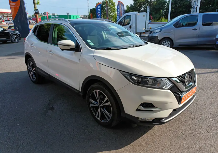 Nissan Qashqai blanc nacré en 3/4 avant droit, avec jantes alliage bicolores et calandre noire brillante.