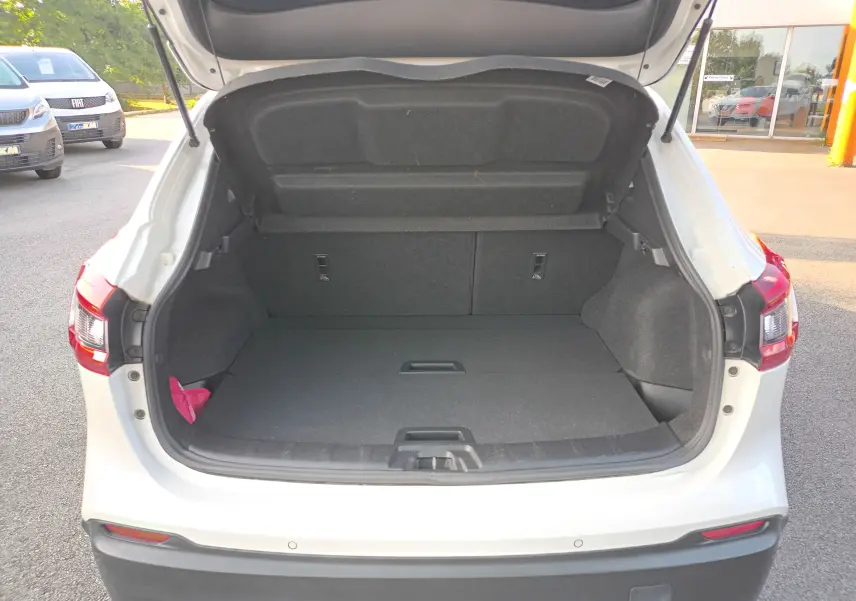 Coffre ouvert vu de l'arrière d'un Nissan Qashqai blanc nacré 2019, espace de chargement vide et propre.