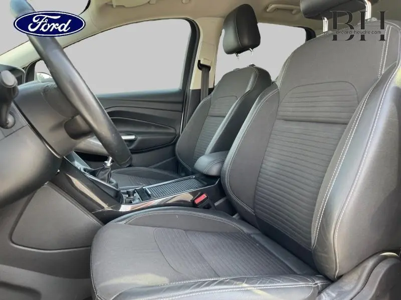 Vue intérieure côté conducteur du Ford Kuga 2017 avec sièges sport noirs et volant cuir multifonction