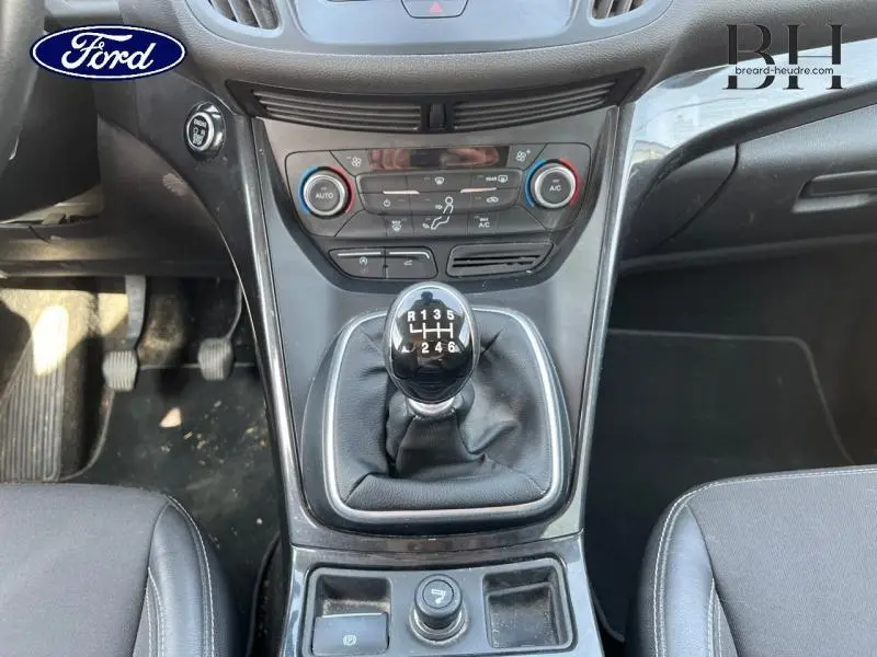 Vue rapprochée de la console centrale du Ford Kuga blanc glacier 2017, mettant en valeur le levier de vitesse manuel et les commandes climatiques.