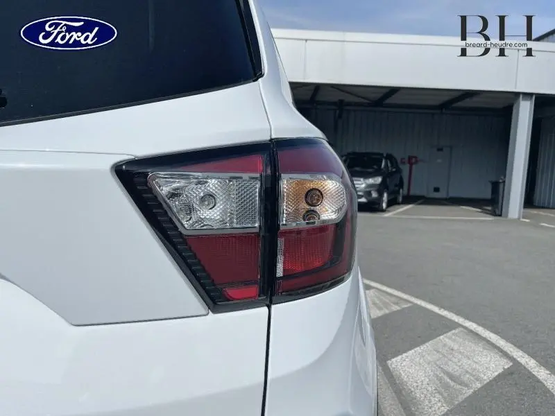 Gros plan sur le feu arrière droit du Ford Kuga blanc Glacier de 2017 avec hayon motorisé visible en arrière-plan.