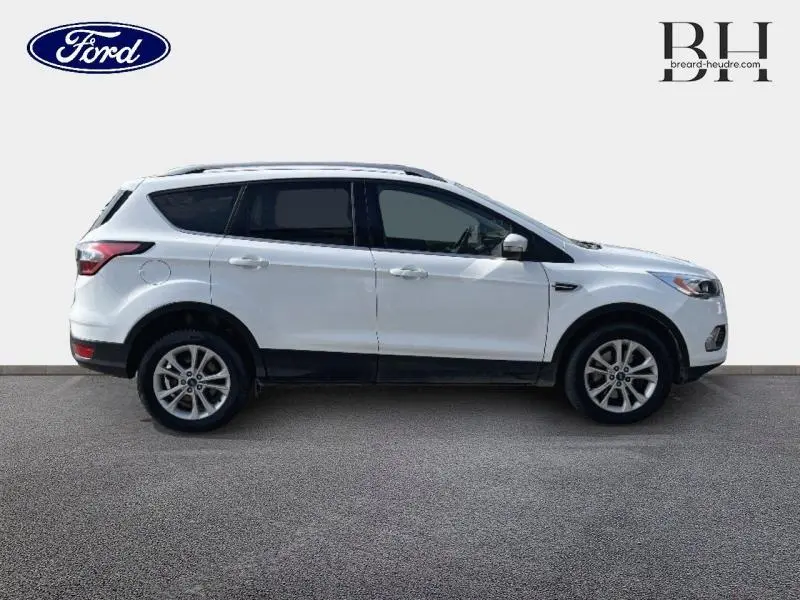 Profil droit d'un Ford Kuga blanc glacier avec barres de toit aluminium et jantes alliage.