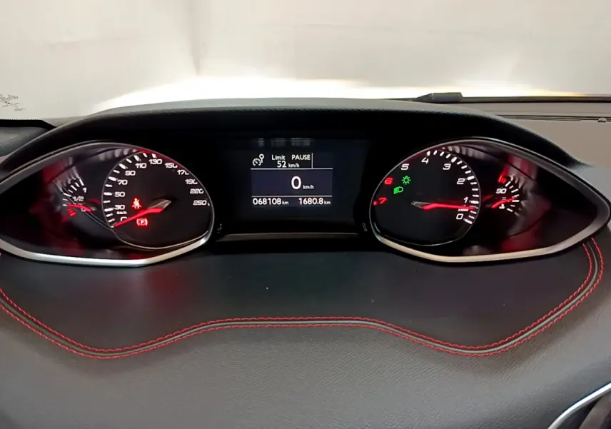 Tableau de bord noir avec surpiqûres rouges de la Peugeot 308 GT Line 2016, affichage digital et compteurs analogiques.