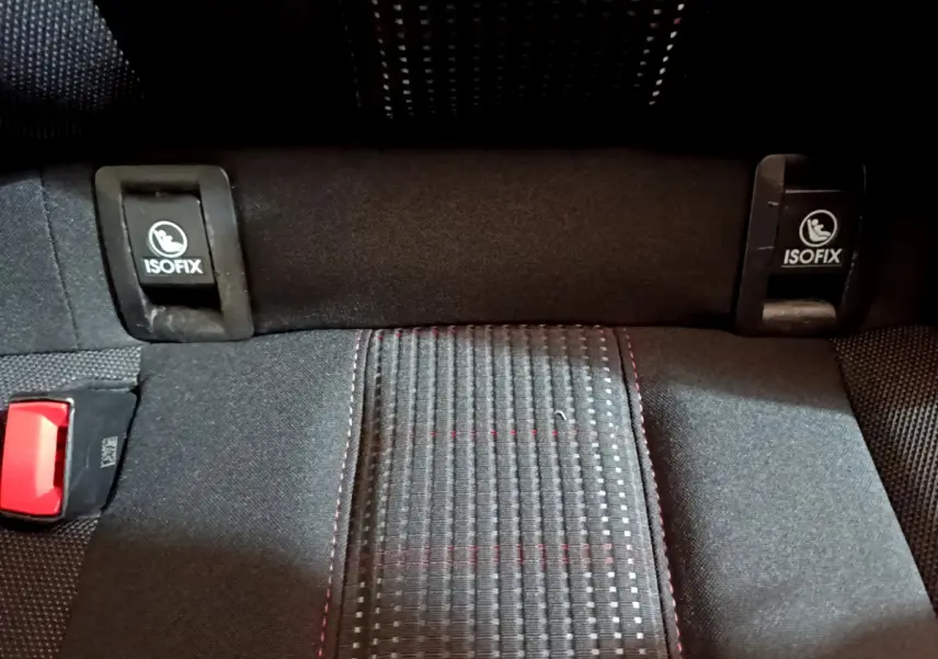 Gros plan sur la banquette arrière noire de la Peugeot 308 avec fixations ISOFIX et couture rouge visible.