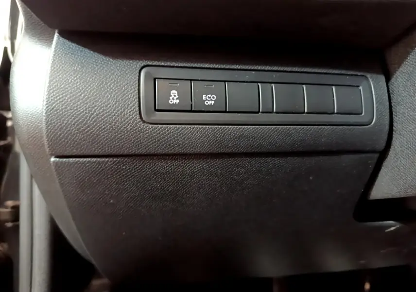 Gros plan sur les boutons de contrôle de stabilité et mode éco dans l'habitacle noir d'une Peugeot 308 GT Line 2016.