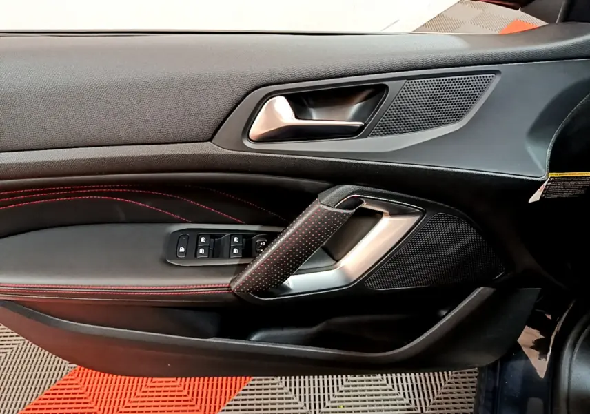 Poignée de porte côté gauche avec surpiqûres rouges et commandes des vitres dans l'habitacle d'une Peugeot 308 GT Line 2016.