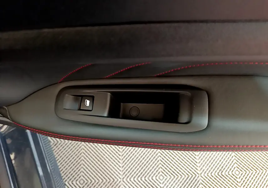 Détail de la poignée intérieure côté gauche avec bouton de lève-vitre sur porte en cuir noir et surpiqûres rouges Peugeot 308 GT Line.