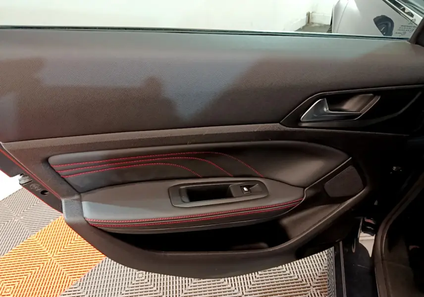 Porte intérieure côté gauche de Peugeot 308 GT Line 2016 en cuir noir avec surpiqûres rouges et poignée métal.
