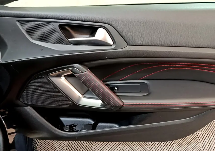Détail de la porte côté gauche de la Peugeot 308 GT Line 2016, avec surpiqûres rouges et poignée en cuir noir perforé.